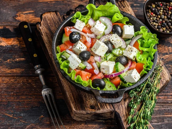 Platos con verduras frescas, ensaladas y alimentos coloridos servidos sobre una mesa de madera